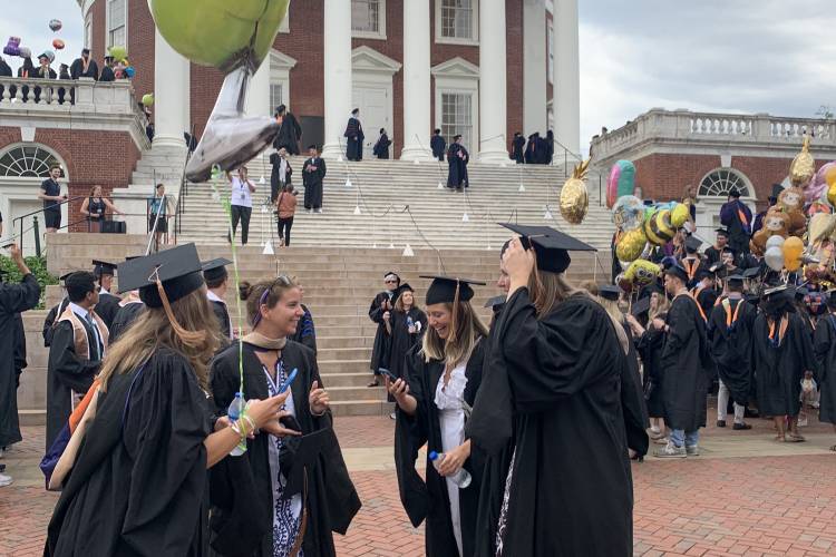 Four friends in graduation robes standing in front of the UVA Rotunda