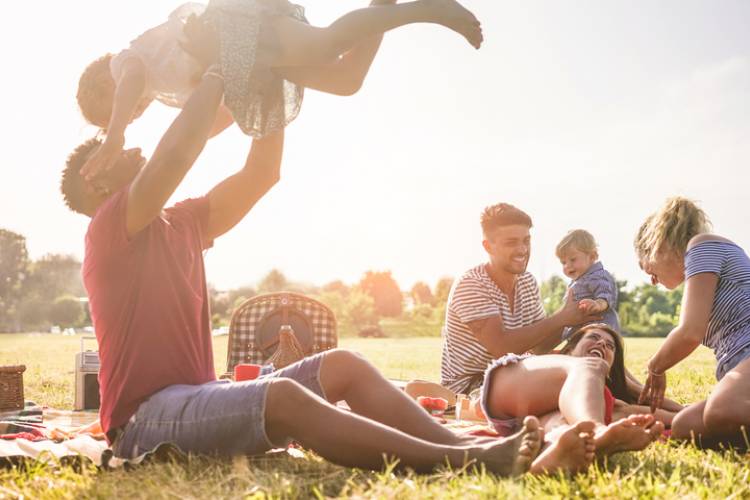 family having picnic on green grass with sunsetting behind them