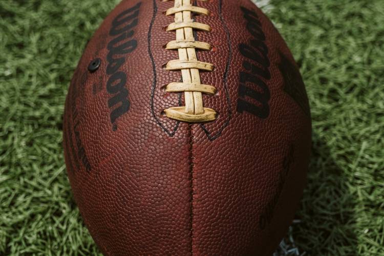 brown, leather football on green field with white lines