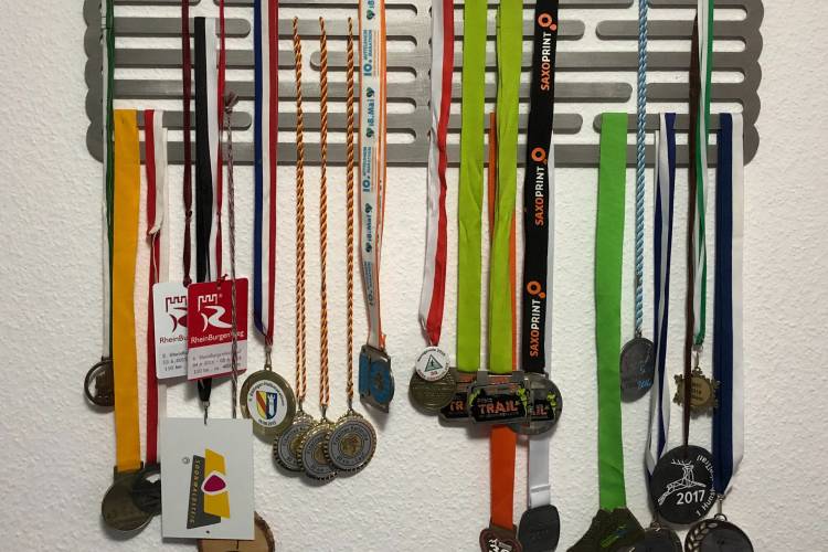 multiple, multi-color running medals hanging on wall