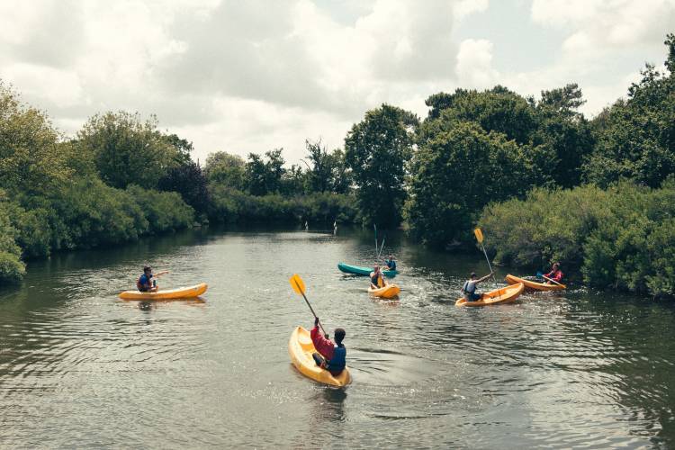 kayakers on river with green trees