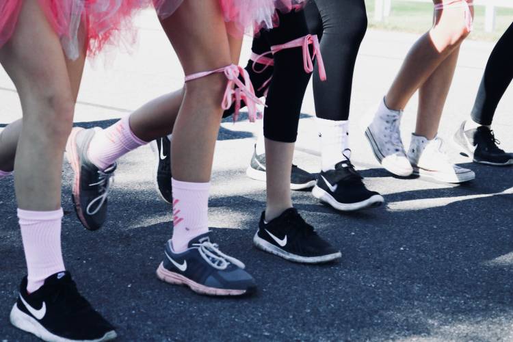 runners lining up at race start with pink ribbon around leg