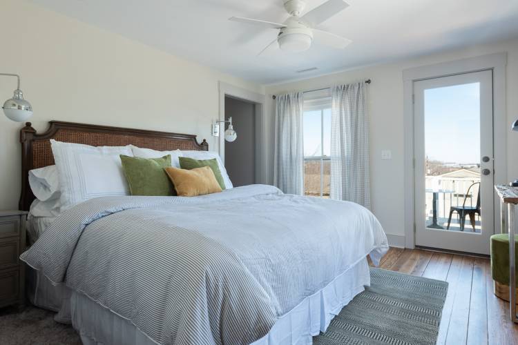 PIctured: Bedroom with brown headboard, blue stripe duvet, and door to balcony